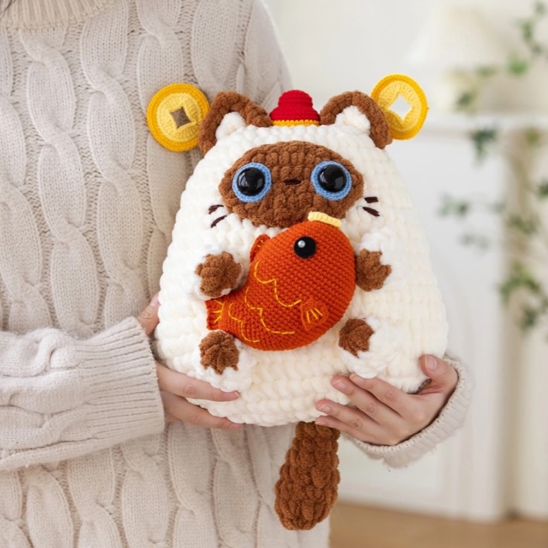 A photo of a DIY material pack for a fortune cat pillow, featuring knitting and crochet supplies.